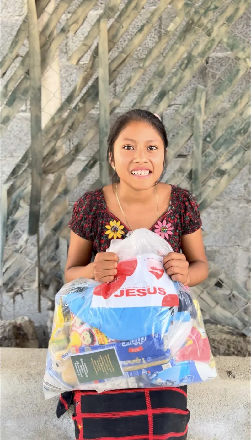 Niña sonriendo con su bolsa de víveres